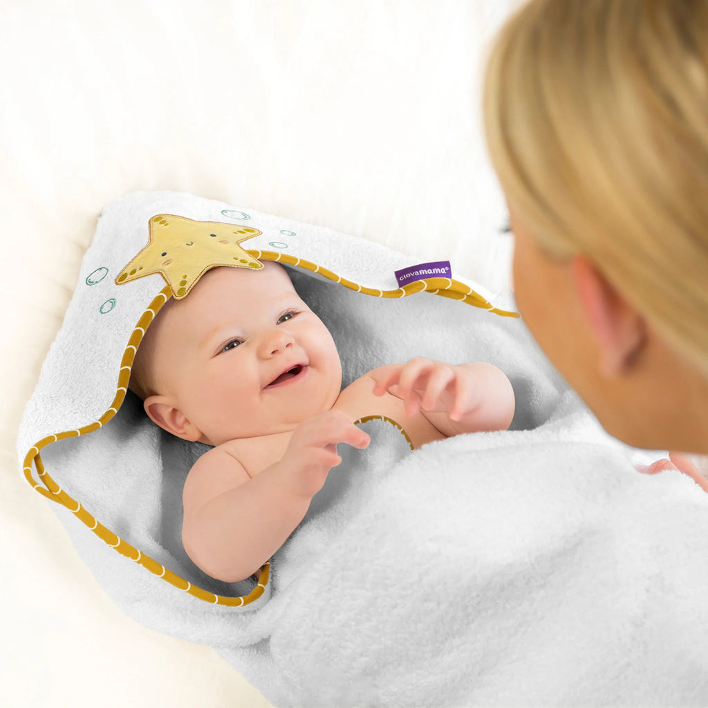 Smiling baby wrapped in ClevaMama bamboo extra large baby bath towel with starfish hood design – ultra-soft, absorbent, hypoallergenic and eco-friendly hooded towel for newborns and toddlers.