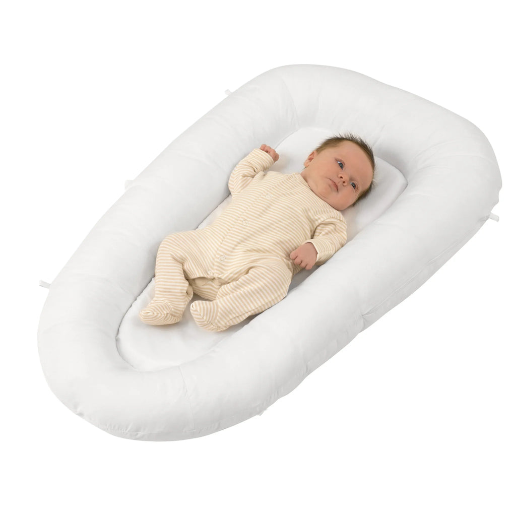 Newborn baby lying in ClevaFoam Baby Pod – white ergonomic baby lounger with soft padded sides, portable pod bed for safe sleep, play and anti-flat head support.