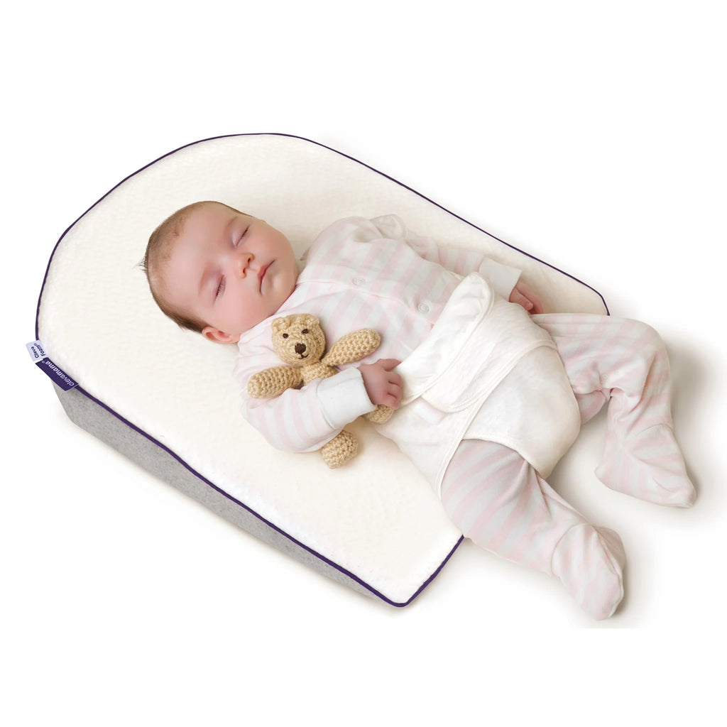 Baby sleeping peacefully on ClevaMama ClevaFoam Elevated Support Pillow with safety harness, designed for newborns 0–6 months to help ease reflux, colic, and congestion, providing safe, elevated sleep support and ultimate comfort.