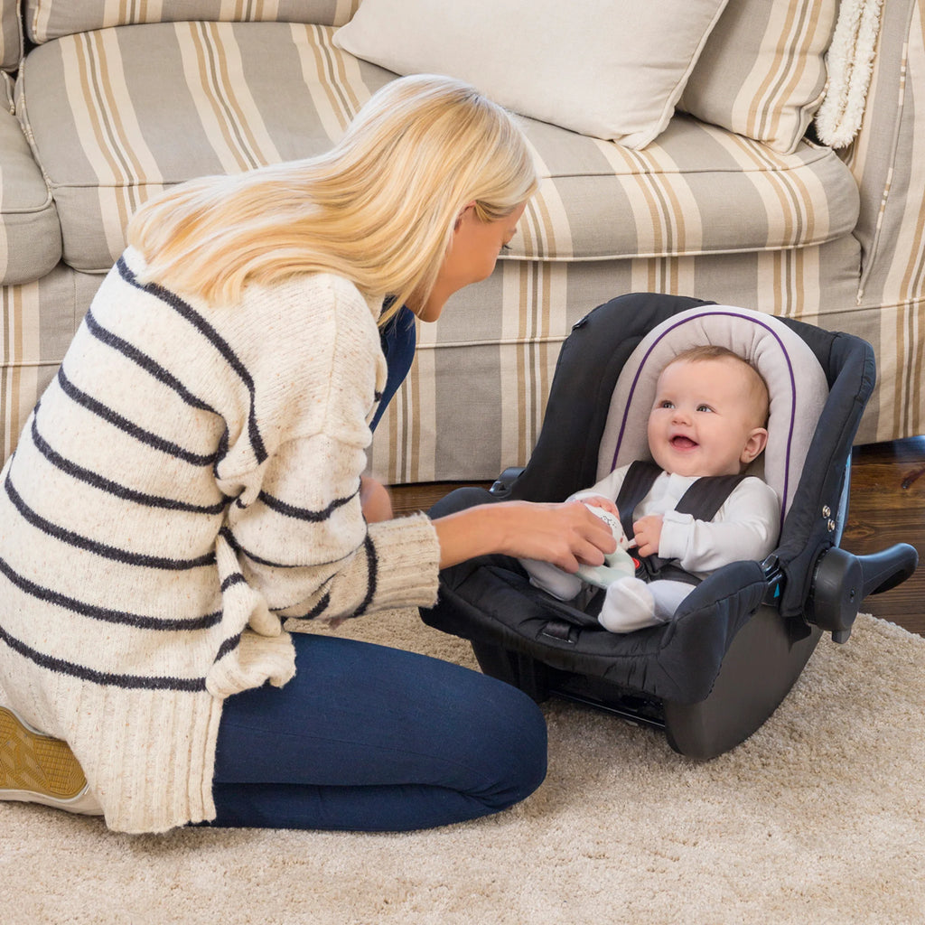 Mother smiling at baby seated in car seat with ClevaFoam Baby Head & Body Support V2, ergonomic infant cushion insert for head, neck and body alignment, breathable hypoallergenic support for safe travel and flat head prevention.