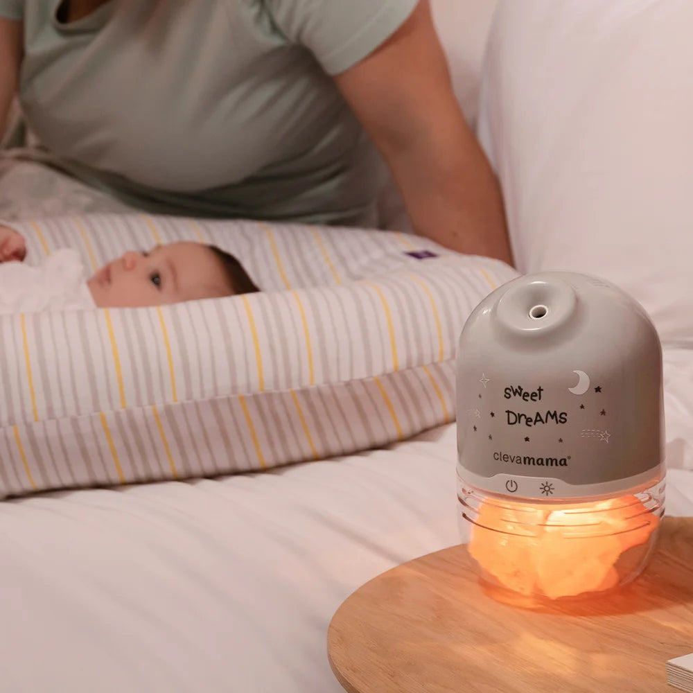 Himalayan salt lamp next to parents bed with baby lying in baby pod.