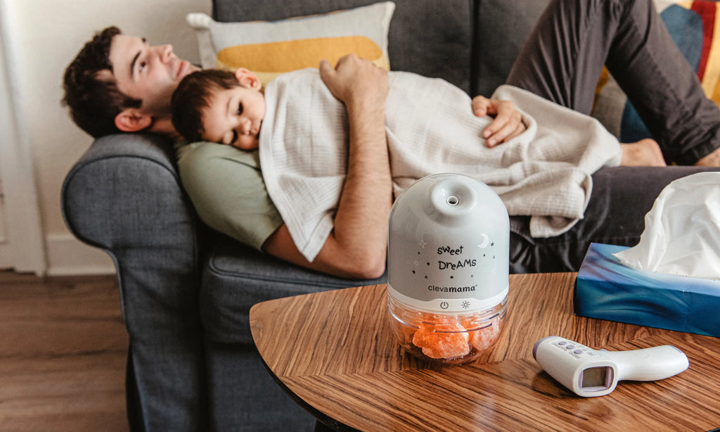 Dad and child lying on sofa with ClevaPure Himalayan salt lamp and thermometer on table.