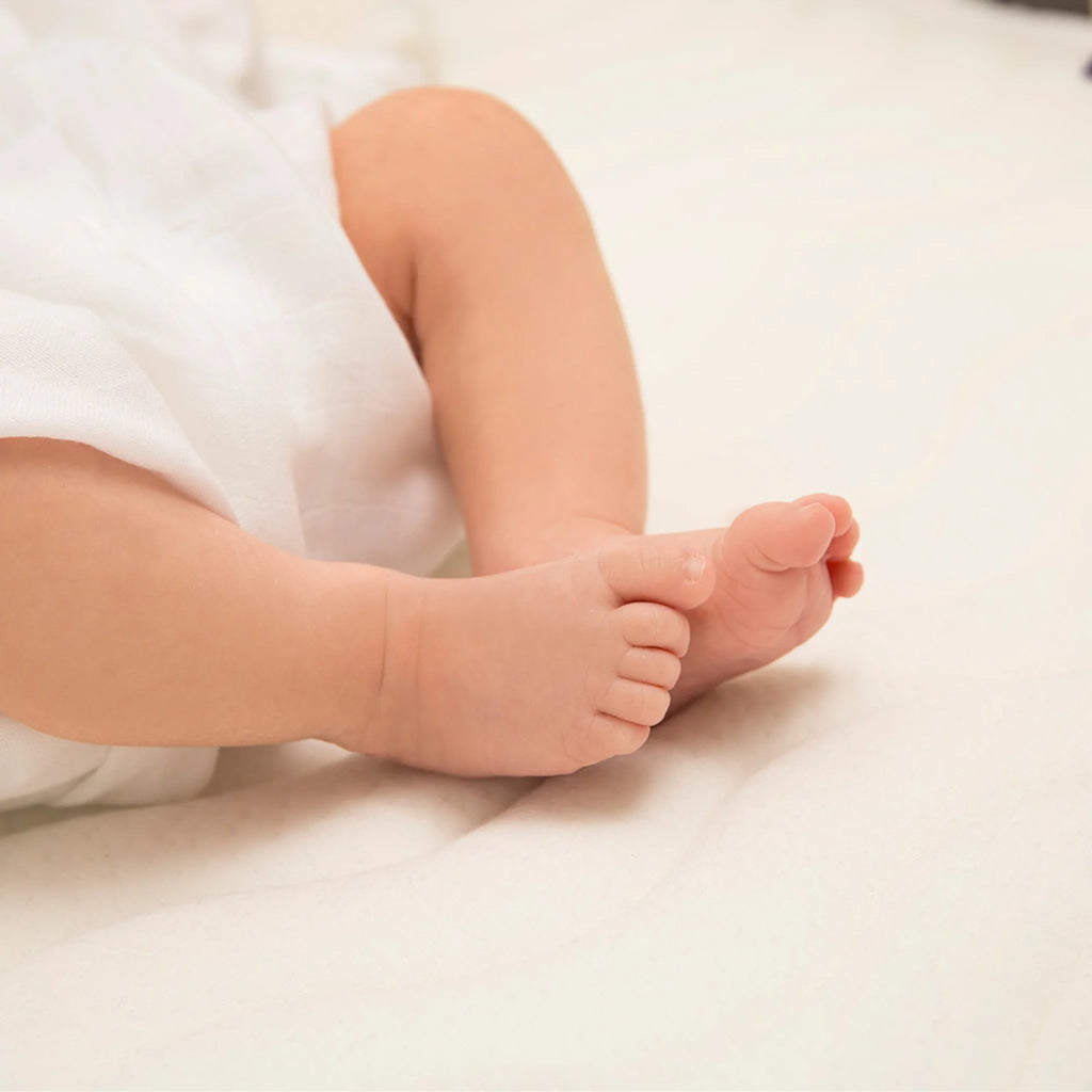 Baby feet resting on ClevaFoam Pocket Sprung Cot Mattress – breathable hypoallergenic OEKO-TEX certified infant mattress for safe and gentle sleep.