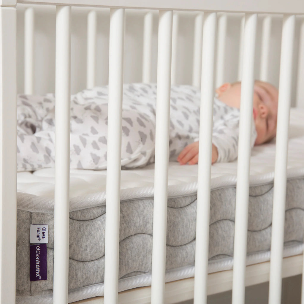 Baby sleeping on ClevaFoam Pocket Sprung Cot Mattress, breathable hypoallergenic OEKO-TEX certified infant mattress with removable washable cover.