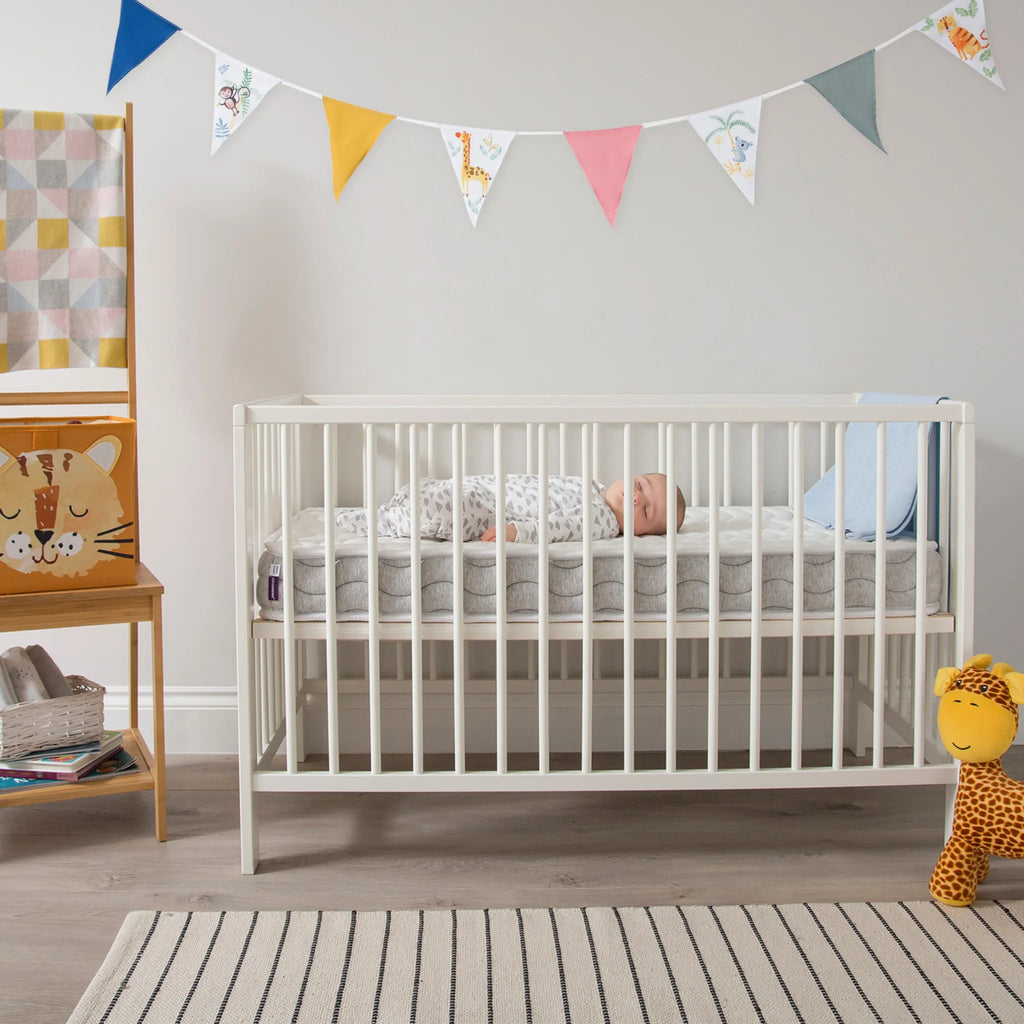 Baby sleeping in white cot on ClevaFoam Pocket Sprung Cot Mattress – breathable hypoallergenic OEKO-TEX certified infant mattress for safe and comfortable sleep.