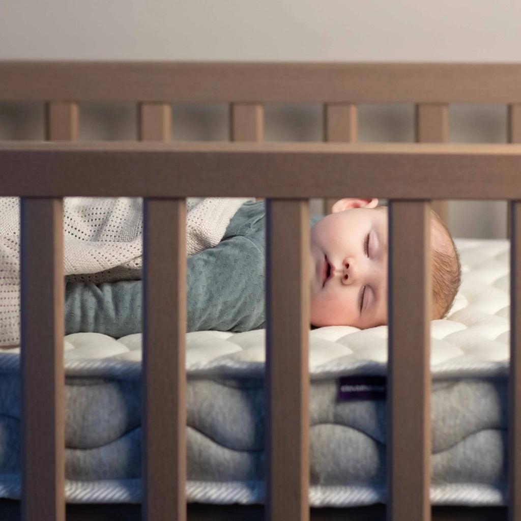 Baby sleeping peacefully on ClevaFoam Pocket Sprung Cot Mattress – breathable hypoallergenic OEKO-TEX certified infant mattress for safe comfortable sleep.