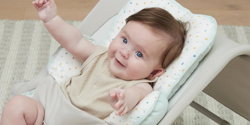 Cute baby smiling in bouncer with terrazzo head and neck support.