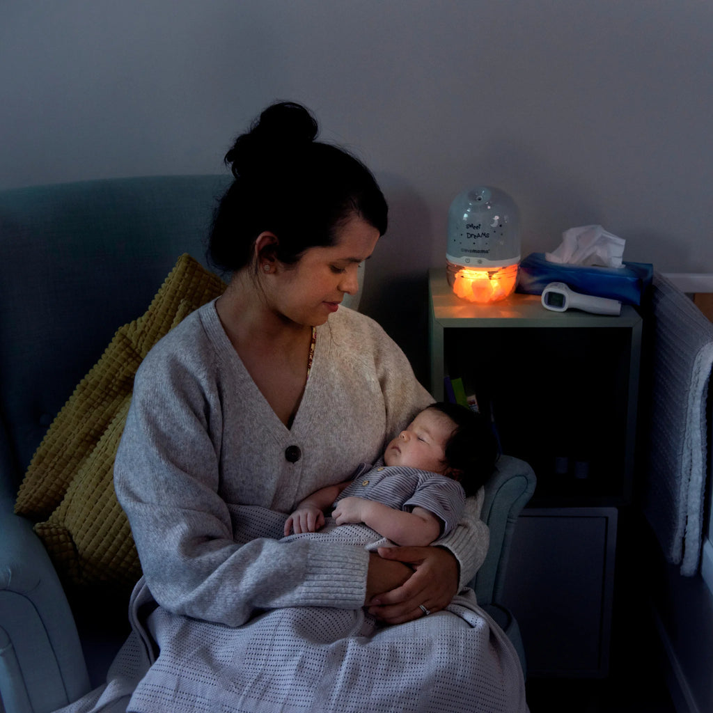 Mother holding baby in nursery with ClevaPure salt lamp humidifier diffuser glowing softly.